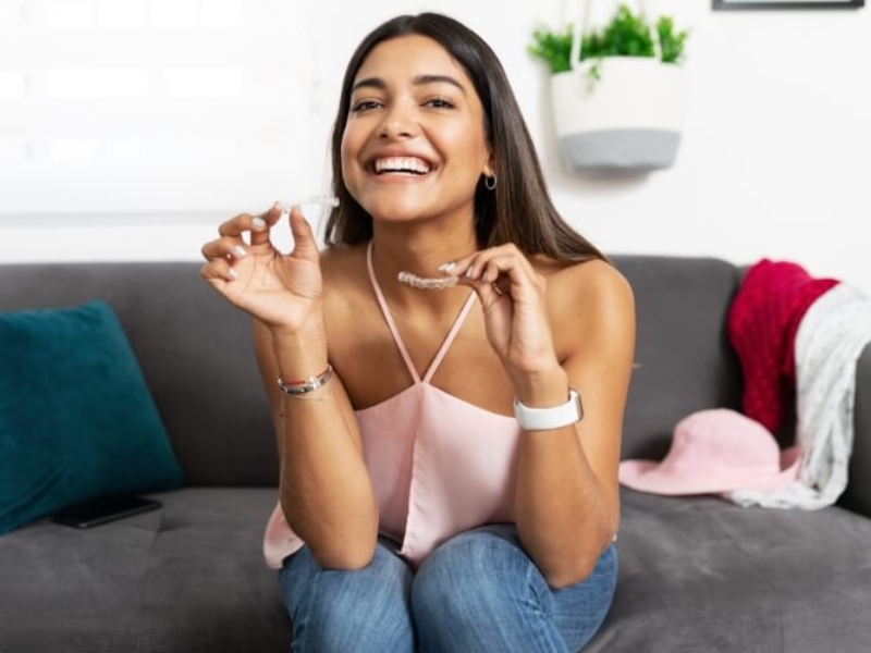 Women smiling while holding clear aligners